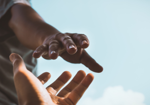 Une personne tend la main pour en aider une autre, symbole de l’aide