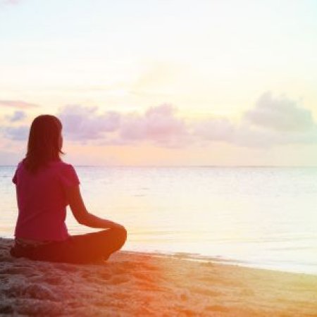 Femme assise en méditation près d'un lac