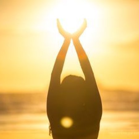 Femme saluant le soleil pendant sa pratique de yoga et astrologie