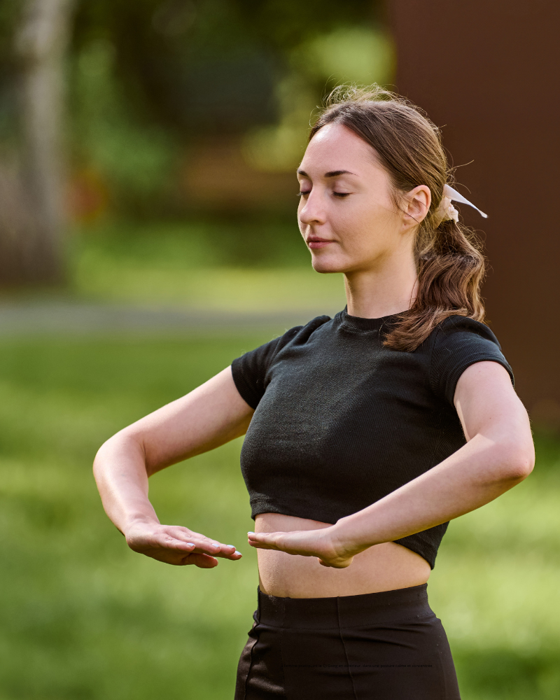 Femme pratiquant le Qi Gong en extérieur, dans une posture calme et concentrée
